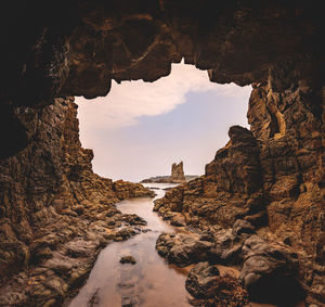 View of rock formation at coast against sky