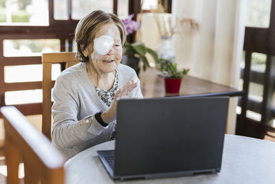 Smiling injured senior woman waving on video call