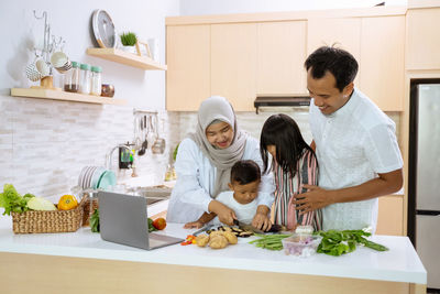 Rear view of mother and daughter in kitchen at home