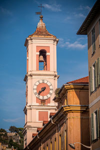 Low angle view of clock tower amidst buildings against sky