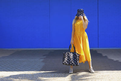 Full length of woman standing against blue wall