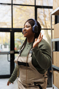 Portrait of young woman standing against building