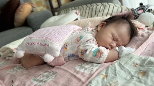 Cute baby boy sleeping on bed at home