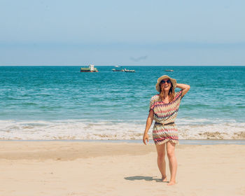 Rear view of woman standing at beach against clear sky