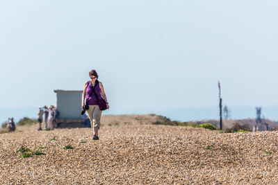 Woman walking on field against clear sky