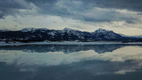 Scenic view of lake by snowcapped mountains against sky