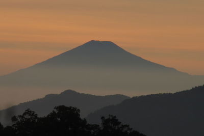 Scenic view of silhouette mountains against orange sky