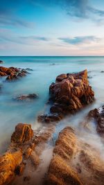 Scenic view of rocks on shore against sky