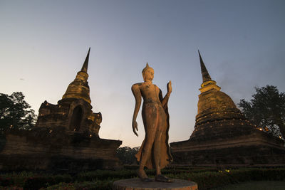 Low angle view of statues on building against sky