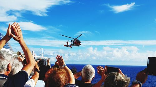 People photographing boats in sea against sky