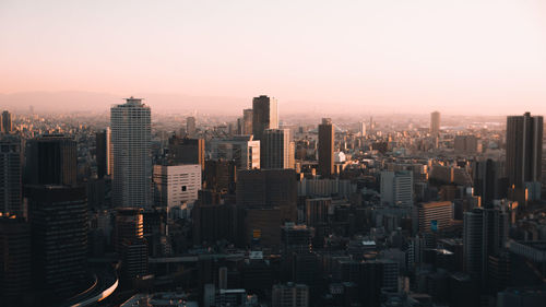 Modern buildings in city against sky during sunset