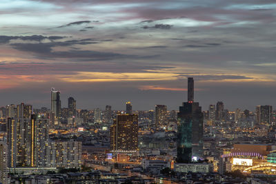 Illuminated buildings in city against sky during sunset