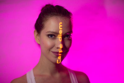 Portrait of young woman against pink background