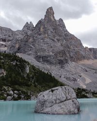 Rock formation by lake against sky