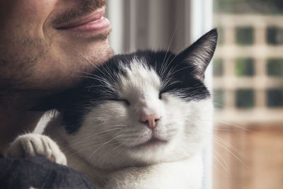 Closeup of a black and white cat cuddled by a man. love relationship between human and cat