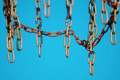 Close-up of chain hanging against blue sky