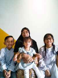 Portrait of cheerful grandmother sitting with grandchildren at home on eid-ul-fitr