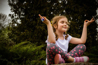 Young woman using mobile phone while sitting on tree