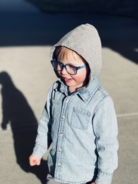 Toddler boy with eyeglasses standing outside 