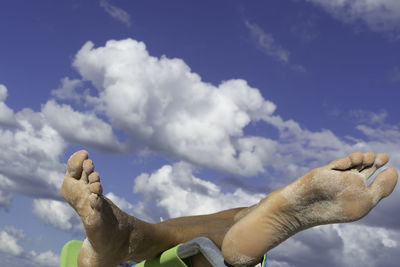 Closeup of female feet with sand against blue sky at a tropical beach in mexico