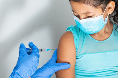 Children's nurse injecting brown girl's arm. doctor's hand with rubber gloves injecting covid-19 