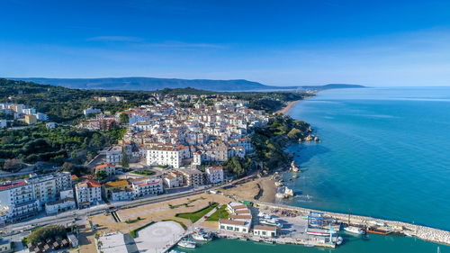 High angle view of townscape by sea against blue sky