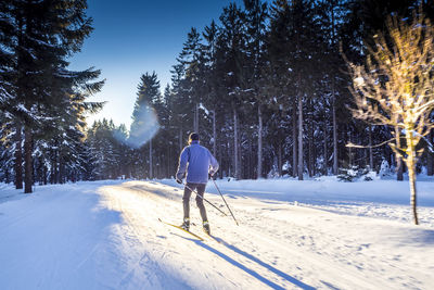 Rear view full length of man skiing on snow covered field