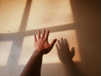 Low section of person touching shadow on window