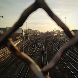 Railroad tracks seen through chainlink fence against sky