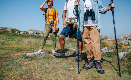 Friends standing on land against sky during hiking