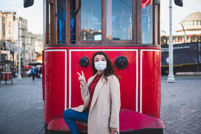 Portrait of woman wearing mask standing against cable car outdoors