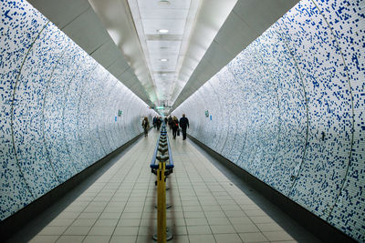 Rear view of people walking in underground walkway