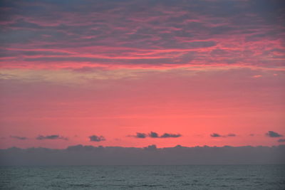 Scenic view of sea against dramatic sky during sunset