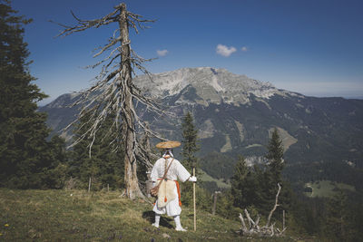Man standing by tree on mountain against sky