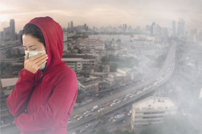 Portrait of man holding umbrella against cityscape in city