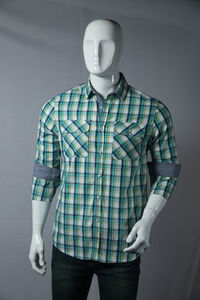 Button down shirt displayed on mannequin against backdrop 