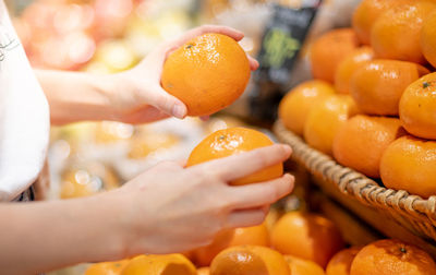 Female two hands holding the orange fruit for spin orange juice at the fresh market, 