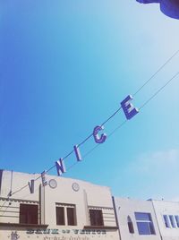 Low angle view of flags hanging against blue sky