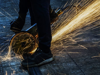 Low section of man using grinder at workshop