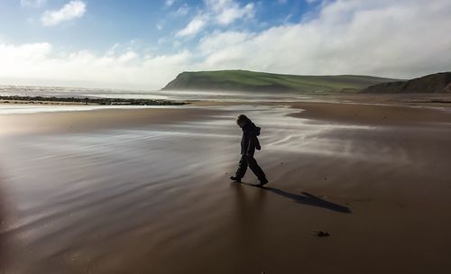 Side view of kid walking on wet shore at beach