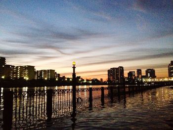 City at waterfront against cloudy sky