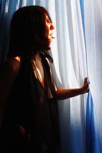 Side view of young woman standing at home