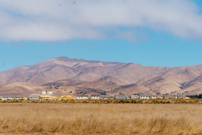 Scenic view of farm field by mountains against sky