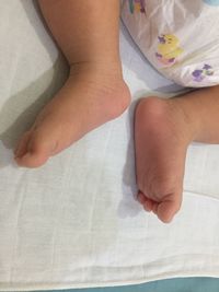 Low section of baby feet on bed