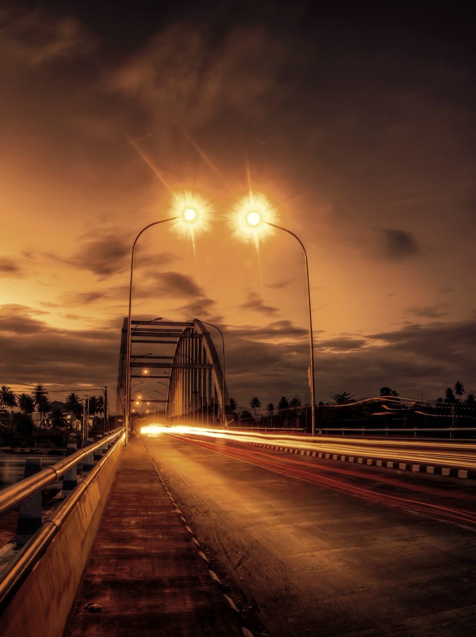 sky, the way forward, sunset, street light, transportation, illuminated, cloud - sky, built structure, architecture, diminishing perspective, railroad track, vanishing point, building exterior, dusk, lighting equipment, city, cloudy, road, orange color, connection