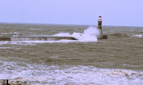 Lighthouse on beach against sky