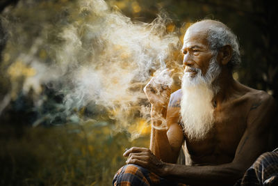 Senior man smoking while sitting outdoors