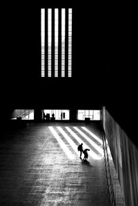 Silhouette man walking in illuminated building