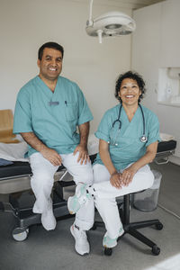 Portrait of smiling male and female healthcare professionals sitting in hospital