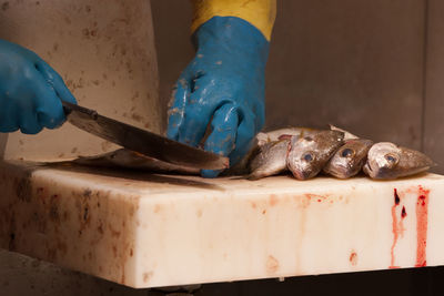 Cropped hands cutting fish in shop for sale